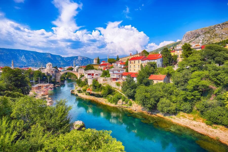 Fantastic Skyline of Mostar with the Mostar Bridge, houses and minarets, during sunny day.